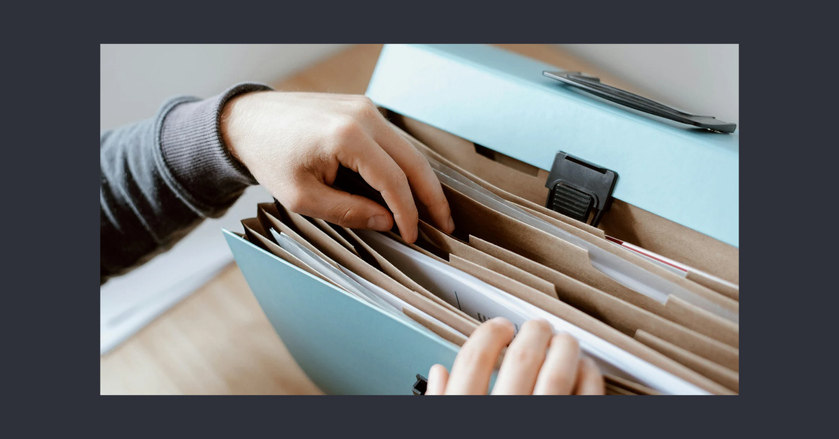 Hands organizing important documents in a labeled file folder — a visual of making an end-of-life plan accessible and actionable.